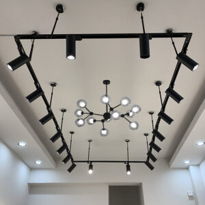 Modern black track lighting system with a decorative chandelier on a white ceiling
