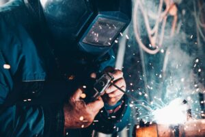 Professional welder using a welding machine to join metal with bright sparks
