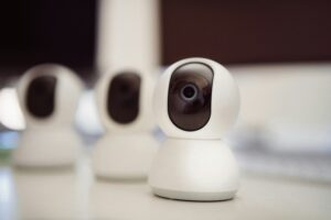 Three white indoor CCTV security cameras with wide-angle lenses positioned on a surface for home surveillance