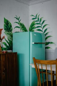 Vintage turquoise refrigerator in a kitchen with green botanical wall art
