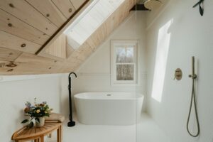 Modern white bathroom with freestanding bathtub, rainfall shower, hexagonal wall tiles and natural wood ceiling
