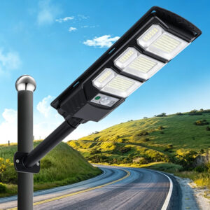 Black solar LED streetlight with multiple LED panels and a motion sensor mounted on a pole beside a winding road.